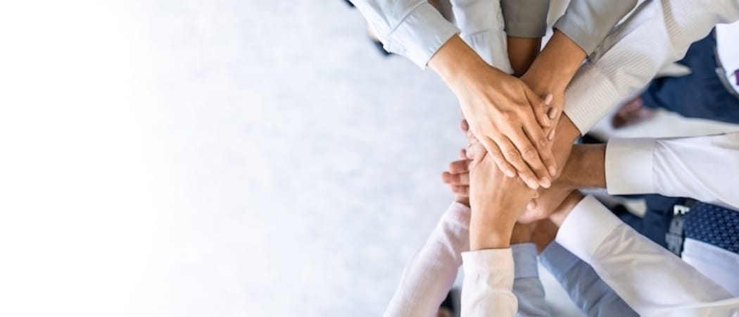 複数の人が手を重ね合わせ、団結やチームワークを表現しているイメージ